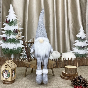 Detail of Christmas knitted gnome with grey hat and long legs in festive holiday setting