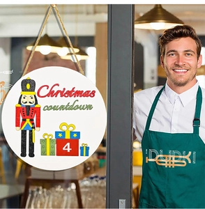 Wooden Christmas countdown calendar sign with nutcracker soldier hanging on a glass door