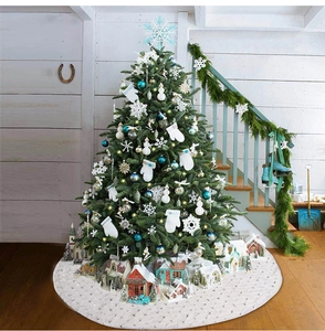 Detailed close-up of white plush Christmas tree skirt with festive holiday village decor