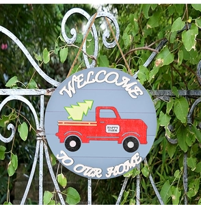 Rustic round wooden door hanger featuring a red vintage truck and Christmas tree on a fence