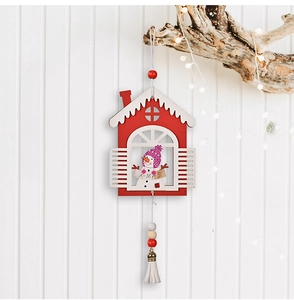 Detailed view of a wooden Christmas cabin ornament with snowman design and white tassel