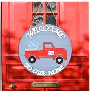 Detail of blue wooden welcome sign with red truck graphic hanging on a red door