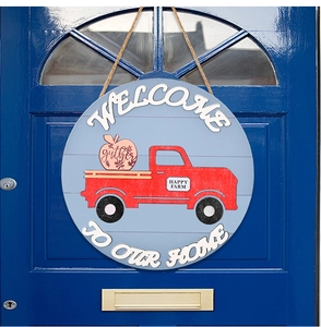 Detail of wooden welcome door sign with vintage red truck and gather motif on blue surface