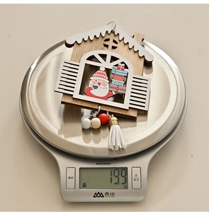 Macro detail of a wooden Christmas house ornament showing weight on a digital scale