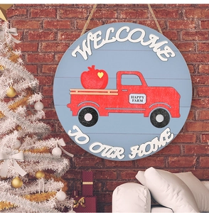 Detail of a round wooden welcome sign with a red vintage farm truck on a brick wall