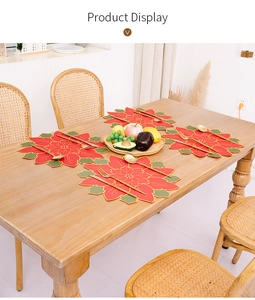 Detail of red Poinsettia placemats with gold embroidery on a wooden dining table