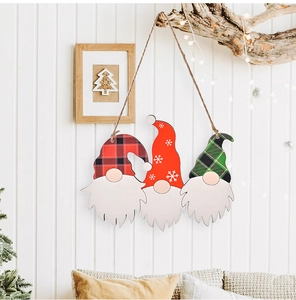 Dettaglio di tre gnomi natalizi in legno appesi a una parete con luci calde festive