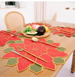 Close-up of red poinsettia Christmas placemat with gold embroidery on wooden table