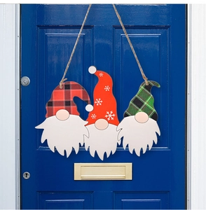 Tre gnomi natalizi in legno appesi a una porta blu scuro come decorazione festiva