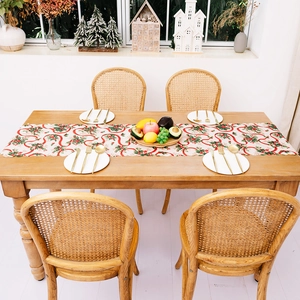 Chemin de table de Noël avec rubans rouges et motifs de houx sur table en bois