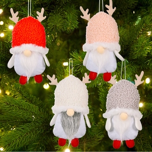 Close-up of four plush Christmas gnomes with reindeer antlers hanging on a festive tree