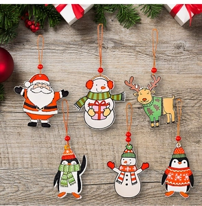 Flat lay of six wooden Christmas ornaments with Santa, snowmen, and penguins on wood background