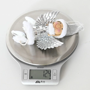 Detail shot showing a lightweight Christmas angel ornament weighing 12.4g on a digital scale