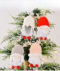 Close-up of four plush Christmas gnomes with reindeer antlers hanging on a festive tree