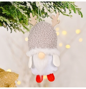 Detail of Christmas gnome with reindeer antlers hanging on snowy pine branch