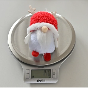 Close-up of a Christmas gnome plush weighing 14g on a scale featuring red antlers
