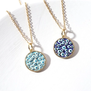 Bohemian gold plated evil eye pendant necklaces with blue enamel details on white tray