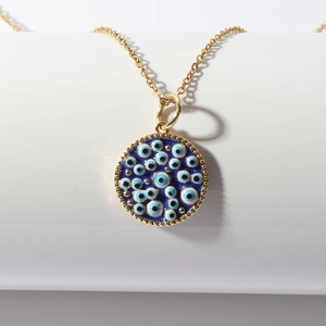 Bohemian gold chain necklace with blue evil eye pendant on white display stand