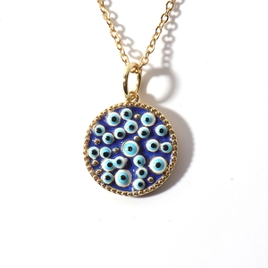 Detailed view of the gold-plated evil eye pendant necklace with blue enamel work