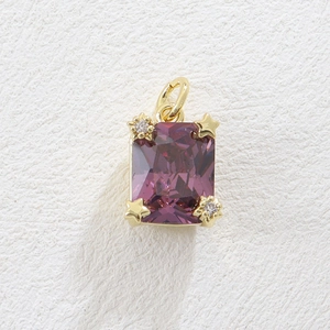 Macro detail of rectangular purple gemstone pendant with gold star and zircon accents
