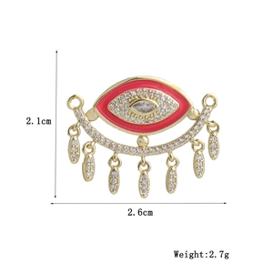Detail of 18k gold plated evil eye charm with red enamel and white zircon tassels