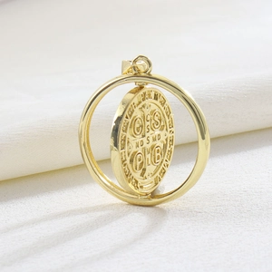 Detailed macro view of a rotating 18k gold Saint Benedict Medal pendant with PAX engraving