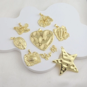 Detailed view of 18k gold plated dinosaur fossil and spider charms on white display