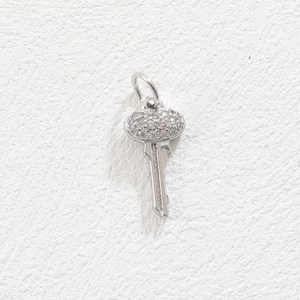 Detailed macro view of a silver-toned key pendant set with shimmering zircons
