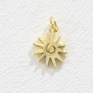 Macro shot of gold sun pendant with spiral center and polished mirror finish for DIY jewelry