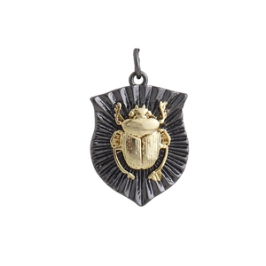 Detailed view of a golden scarab pendant with a black ribbed shield base and hanging loop