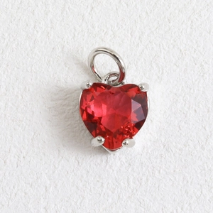 Gros plan d'un pendentif coeur en pierre rouge avec sertissage à quatre griffes argenté