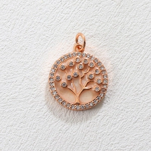 Macro detail of a rose gold Tree of Life charm pendant with crystals and pink enamel