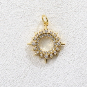 Macro detail of gold sunburst pendant with white zircon inlay and celestial compass design