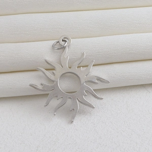 Vue détaillée du pendentif soleil argenté avec rayons enflammés et centre évidé