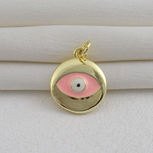 Detalle de colgante de ojo turco chapado en oro de 18k con esmalte rosa sobre tela blanca