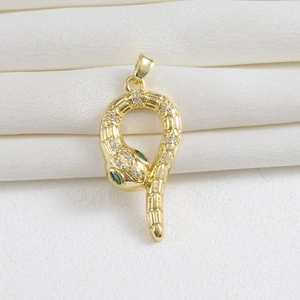 Detail of 18k gold plated snake pendant with sparkling crystals and green gem eyes