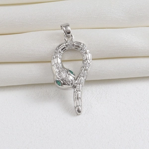 Detailed view of silver snake pendant with pave crystals and green gemstone eyes