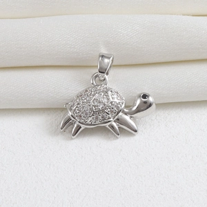 Macro shot of silver turtle pendant with white zircon pavé and black gemstone eyes