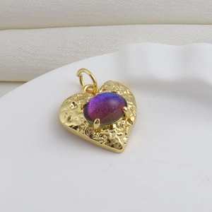 Vue macro d'un pendentif cœur en or 18k avec texture martelée et pierre violette