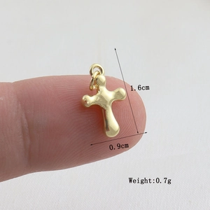 Macro shot of gold cross pendant with dimensions 1.6cm by 0.9cm and 0.7g weight