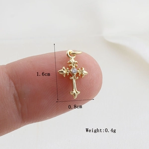 Detailed view of a gold cross pendant with fleur-de-lis design and center zircon crystal