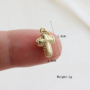 Detailed view of a small golden cross pendant measuring 1.6cm by 0.9cm and weighing 1g
