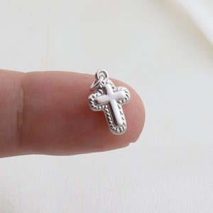 Macro detail of layered cross pendant charm with vintage textured edges and silver finish