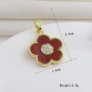 Vue macro du pendentif fleur en or 18k avec pétales rouges et détails en zircon blanc