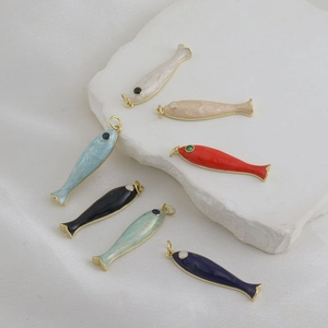 Detailed view of colorful enamel fish charms with golden metal edges for jewelry making