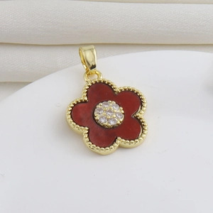 Détail d'un pendentif fleur aux pétales rouges, bordure dorée et centre en cristal