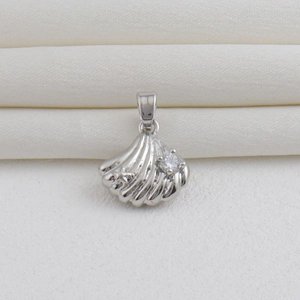 Macro shot of silver shell pendant with a sparkling zircon on beige satin fabric