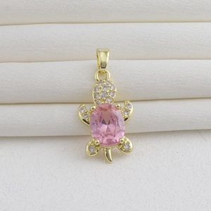 Macro detail of 18k gold plated turtle pendant with pink gemstone and white crystals