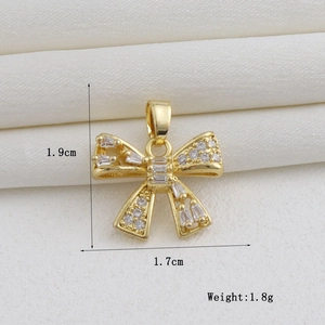 Detailed view of an 18k gold plated bow pendant with white zircon stones on white silk