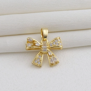Detailed view of an 18k gold plated bow pendant with sparkling white cubic zirconia stones